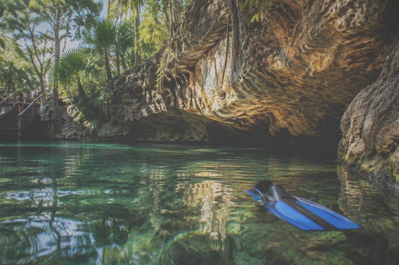 Sunlit freshwater cavern pool with clear water and limestone walls