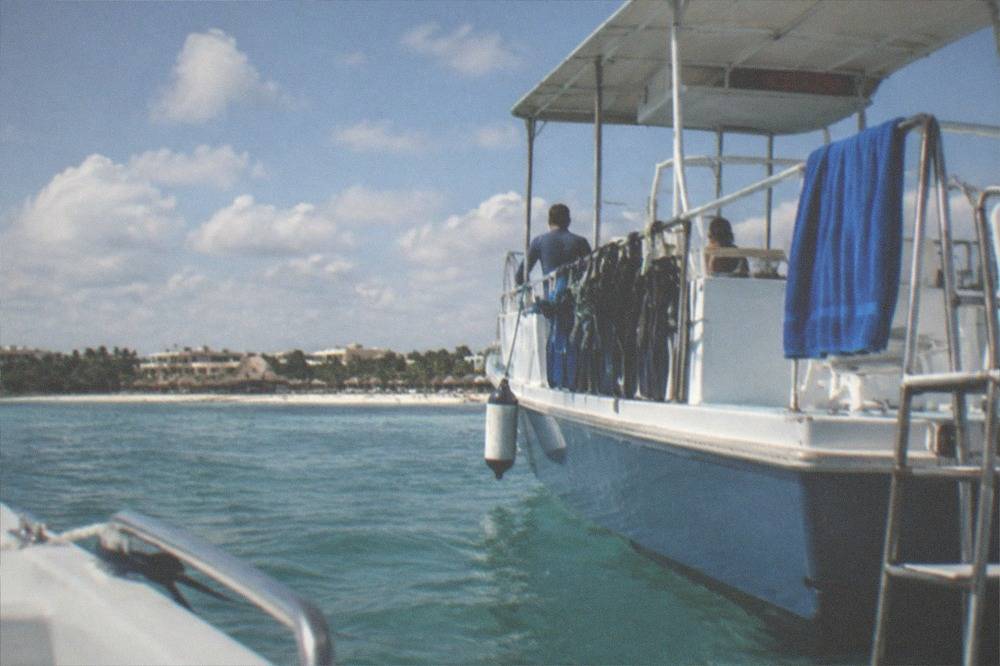 A snorkel boat anchored over a reef with calm sea and scattered clouds