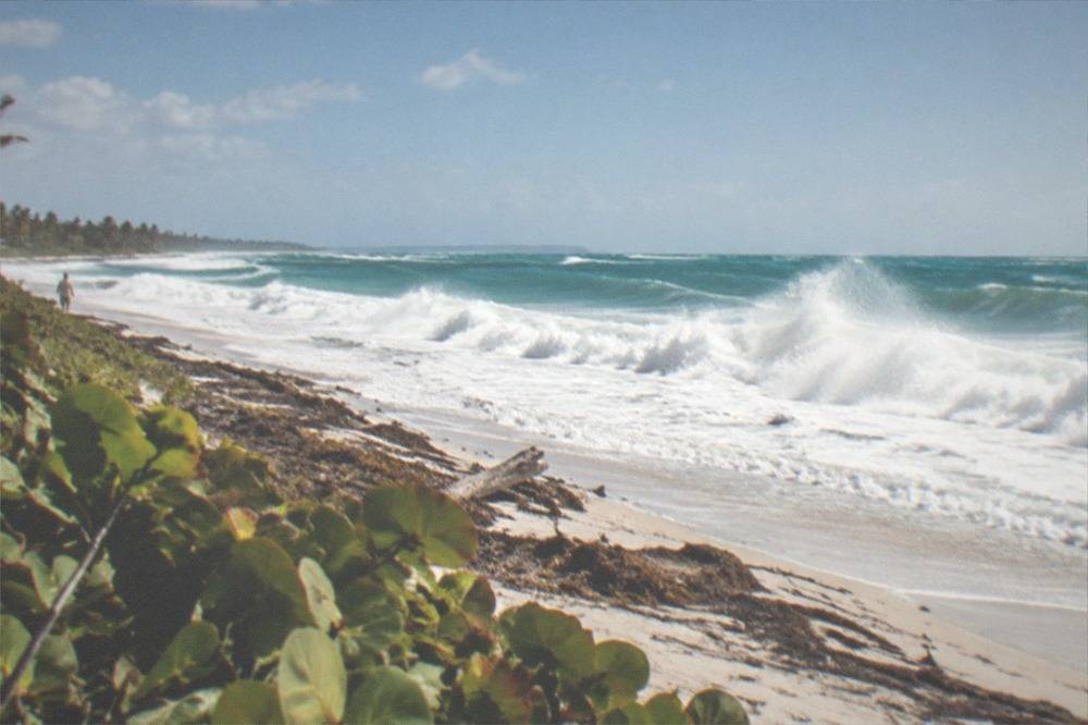 Empty east-facing Cozumel beach with waves breaking under a bright sky