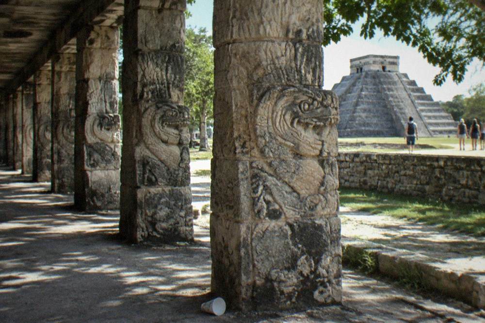 Rows of carved serpent columns and stone platforms at the Temple of the Warriors complex in bright daylight
