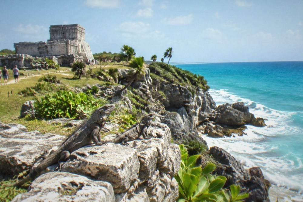 Ancient stone ruins on a grassy cliff above the Caribbean Sea with waves below