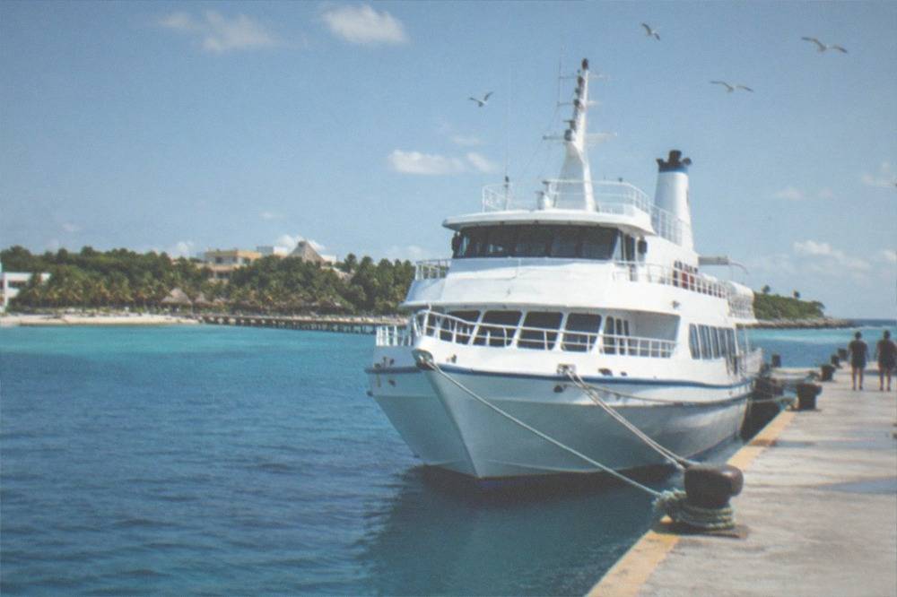 Passenger ferry at a pier on clear blue Caribbean water with the island coastline beyond