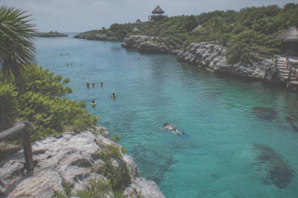 Turquoise natural inlet ringed by limestone walls and dense jungle vegetation