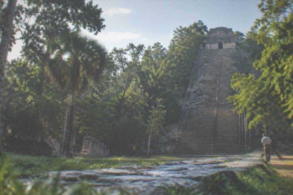 Ancient stone pyramid rising above dense green jungle under a bright sky