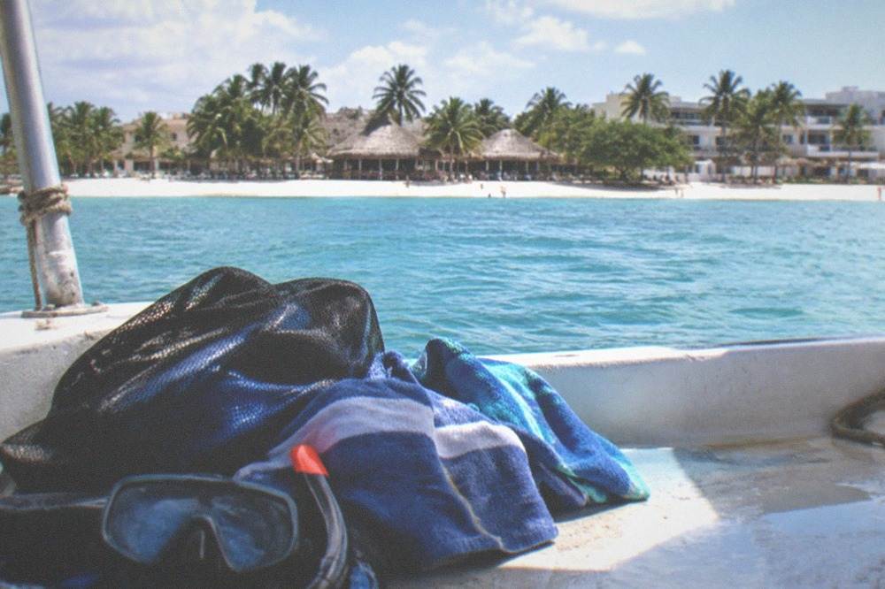 Snorkel gear and towels laid out on a boat deck beside a mesh equipment bag