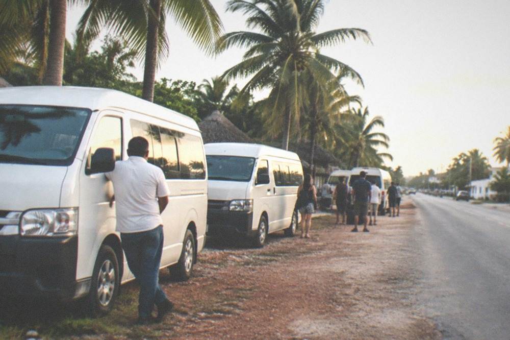 Highway roadside pickup area with vans and palm trees under morning light
